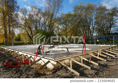Underfloor heating system installation with plastic pipes in concrete base, house construction site 133004685