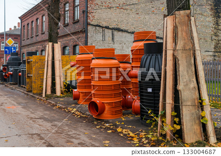 Plastic manhole wells and drainage pipes stacked at urban street construction site in autumn 133004687