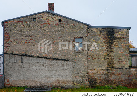 Old weathered brick wall of abandoned building with cracks and damaged window in urban area 133004688