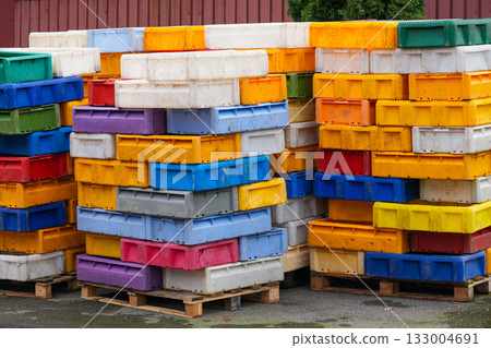 Colorful plastic fish boxes stacked on wooden pallets in a harbor storage area 133004691