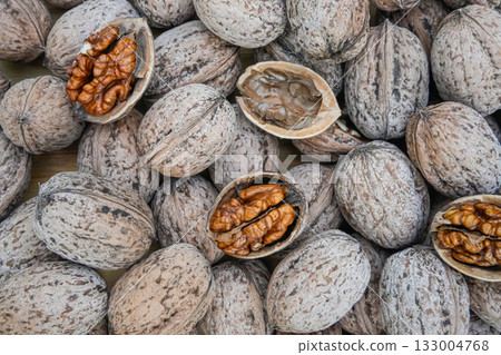 Top view of mixed walnuts with three open nuts, one empty shell, and several closed ones. Natural composition highlighting textures and details of organic food. Ideal for background, nutrition, and Top view of mixed walnuts with three open nuts, one empty shell, and several closed ones. Natural composition highlighting textures and details of organic food. Ideal for background, nutrition, and 133004768