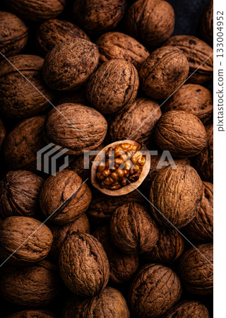 Cracked walnut in pile of whole walnuts 133004952