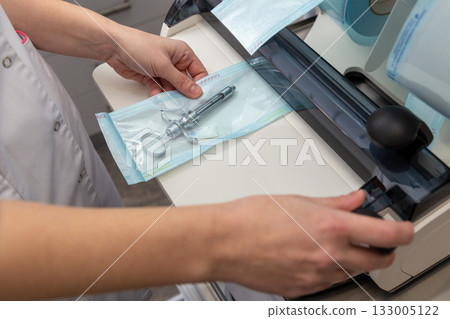 A dental professional packages a metal dental anesthetic syringe in a sterilization pouch 133005122