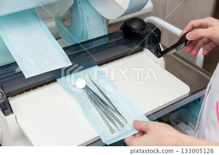 A dental professional packages a set of metal dental instruments 133005126