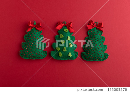 Handmade Felt Christmas Tree Ornaments with Bows on Red Background Handmade Felt Christmas Tree Ornaments with Bows on Red Background 133005276