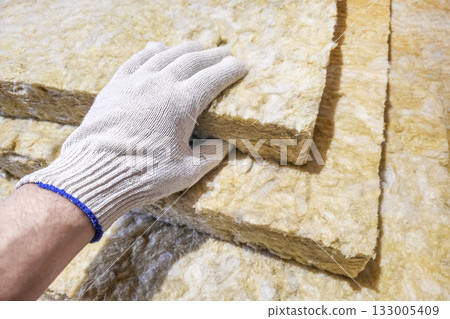 A gloved hand takes a sheet of thermal insulation material. A gloved hand takes a sheet of thermal insulation material. 133005409