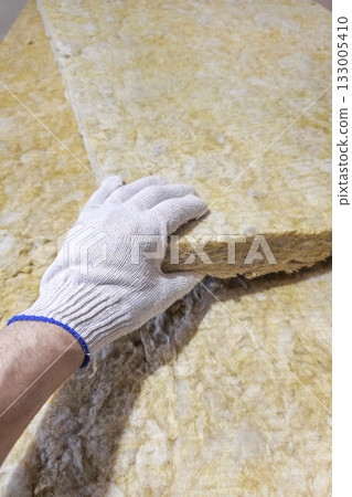 a gloved hand takes a sheet of thermal insulation material a gloved hand takes a sheet of thermal insulation material 133005410