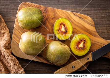 Red kiwi fruit on cutting board on wooden table. Top view. 133005433