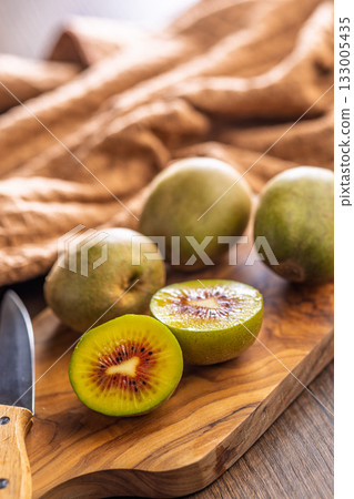 Red kiwi fruit on cutting board on wooden table. Red kiwi fruit on cutting board on wooden table. 133005435
