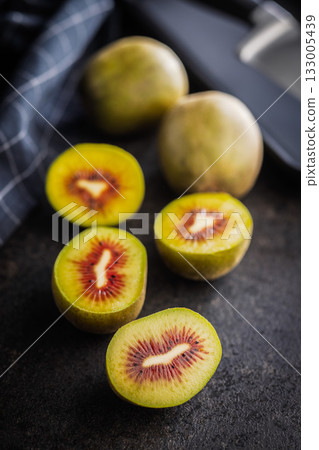 Red kiwi fruit on black table. 133005439