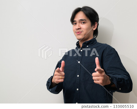 Portrait of handsome Young Asian Thai man smiling and giving thumbs up against white background 133005510