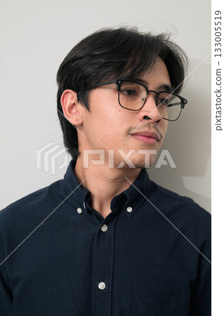 Portrait of handsome young Asian Thai man wearing eyeglasses thinking against white background Portrait of handsome young Asian Thai man wearing eyeglasses thinking against white background 133005519
