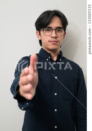 Portrait of handsome young Asian Thai man wearing eyeglasses offering handshake Portrait of handsome young Asian Thai man wearing eyeglasses offering handshake 133005535
