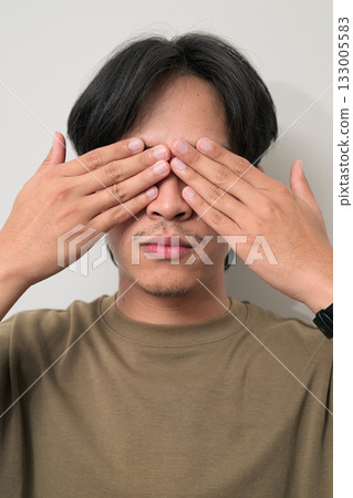 Portrait of handsome Young Asian Thai man with see no evil gesture against white background 133005583