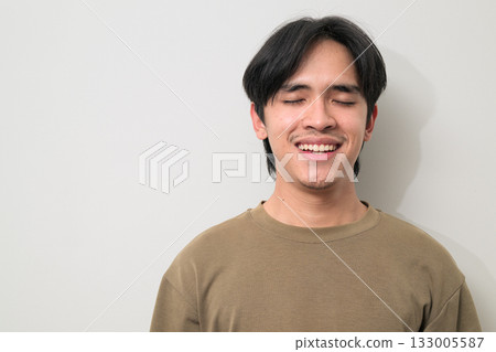 Portrait of handsome Young Asian Thai man with eyes closed against white background 133005587