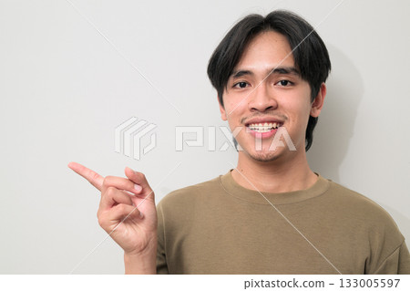 Portrait of handsome Young Asian Thai man pointing finger against white background Portrait of handsome Young Asian Thai man pointing finger against white background 133005597