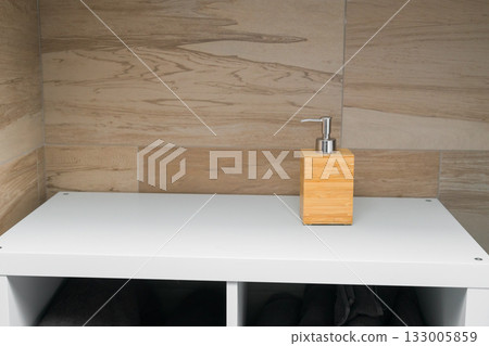 Soap dispenser on white shelf. Copy space. Cleanliness, routine, and simplicity in modern interior. 133005859