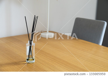 Reed diffuser on wooden table. Scent, calmness, and home fragrance in peaceful minimalist space. Copy space 133005950