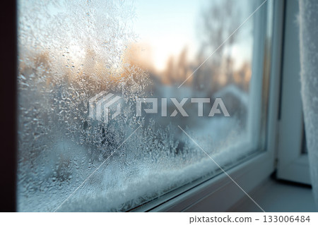 Frosted window with ice crystals and blurred winter trees outside 133006484