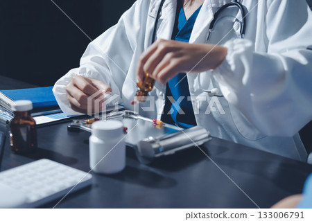 Female doctor holding a medicine bottle is checking the quality of medicine for any side effects the patient or not and recording patient information at the hospital. medical and health care concept Female doctor holding a medicine bottle is checking the quality of medicine for any side effects the patient or not and recording patient information at the hospital. medical and health care concept 133006791