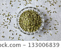 Fennel in a crystal bowl scattered on a gray concrete table, top view. 133006839