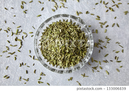 Fennel in a crystal bowl scattered on a gray concrete table, top view. 133006839
