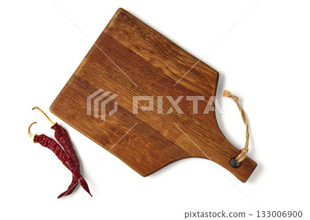 Brown wooden cutting board and two hot red peppers isolated on white background. 133006900