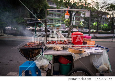 Vendor stall selling junk unhealthy food on walking street in Bangkok, meat grilling on mobile cart. Vendor stall selling junk unhealthy food on walking street in Bangkok, meat grilling on mobile cart. 133007036