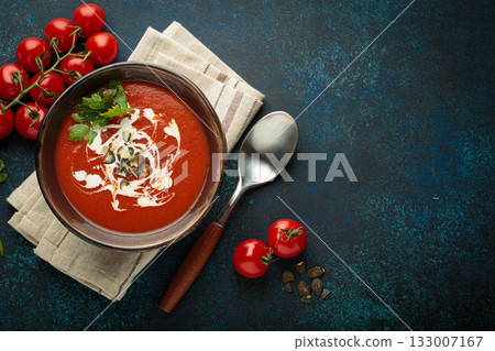 Tomato soup with cream, pumpkin seeds and herbs on blue background top view, copy space 133007167