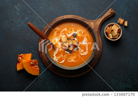 Pumpkin soup croutons cream fresh pumpkin slices wooden board dark background autumn winter 133007170