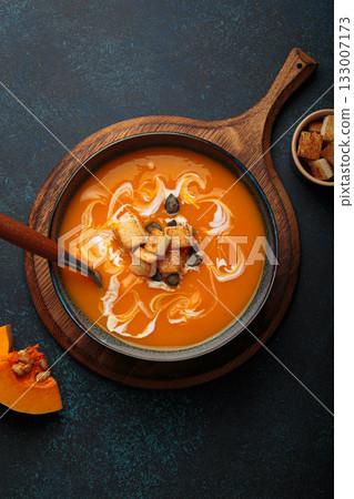 Pumpkin soup croutons cream fresh pumpkin slices wooden board dark background autumn winter Pumpkin soup croutons cream fresh pumpkin slices wooden board dark background autumn winter 133007173