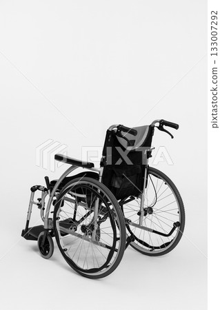 A Simple Black and White Wheelchair Positioned in a Clean and Minimalistic Setting A Simple Black and White Wheelchair Positioned in a Clean and Minimalistic Setting 133007292