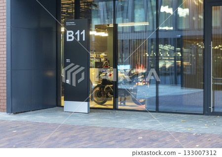 A modern business center with a glass facade and contemporary architecture. A motorcycle is parked inside. 133007312