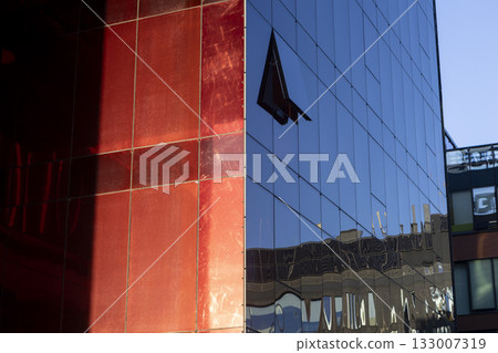 A modern business center with a red glass facade and contemporary architecture A modern business center with a red glass facade and contemporary architecture 133007319