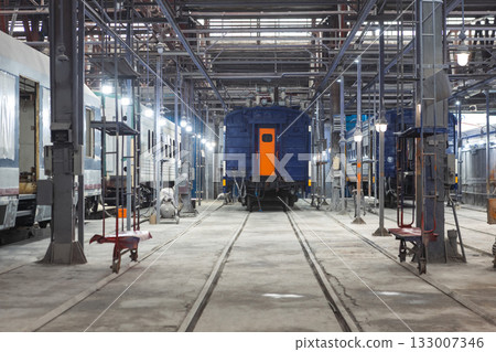 Train carriages stand in a workshop at a train construction and repair plant. Train carriages stand in a workshop at a train construction and repair plant. 133007346