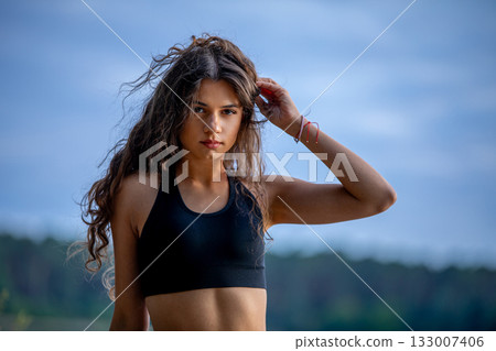 A Young Woman in a Sporty Pose by the Beautiful Water, Radiating Confidence and Energy A Young Woman in a Sporty Pose by the Beautiful Water, Radiating Confidence and Energy 133007406