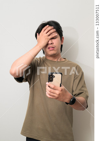 Portrait of handsome young Asian Thai man using phone texting against white background Portrait of handsome young Asian Thai man using phone texting against white background 133007511