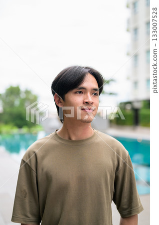 Portrait of handsome Young Asian Thai man outdoors next to swimming pool during summer thinking 133007528