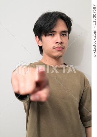 Portrait of handsome Young Asian Thai man pointing finger at camera against white background Portrait of handsome Young Asian Thai man pointing finger at camera against white background 133007597