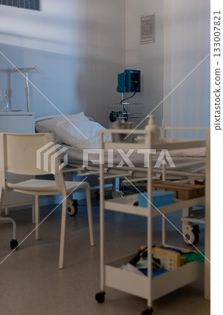 A clean and organized hospital room that features a bed along with necessary medical equipment A clean and organized hospital room that features a bed along with necessary medical equipment 133007821
