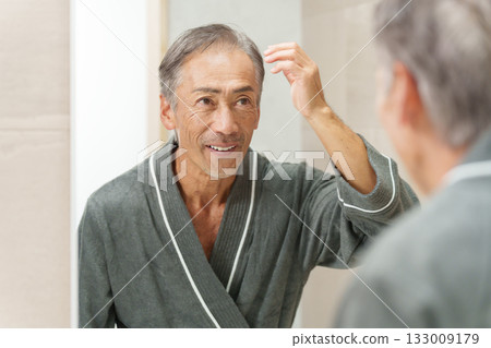 Senior man (bald/thinning hair) checking his hair in the bathroom Senior man (bald/thinning hair) checking his hair in the bathroom 133009179