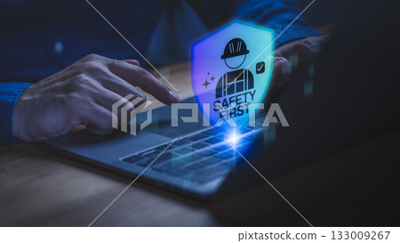 Close up of a person using a laptop with a glowing digital shield icon showing Safety First, symbolizing workplace safety, cyber protection, risk management and secure technology. 133009267