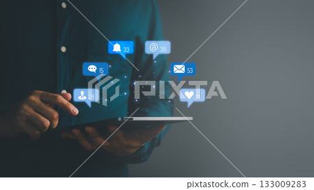 Man using digital tablet with floating social media notification icons, symbolizing online communication, messaging, email, followers, likes, and digital network connectivity. 133009283