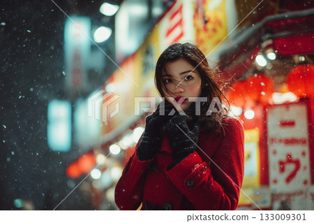 A woman in a red coat standing on a winter night | A sentimental moment surrounded by snow and neon lights 133009301