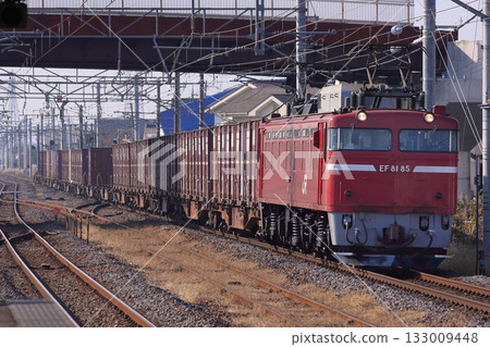 一列由EF81-85型機車牽引的貨運列車，拖著長長的貨車車廂，行駛在常磐線上。拍攝於2010年12月2日。 133009448