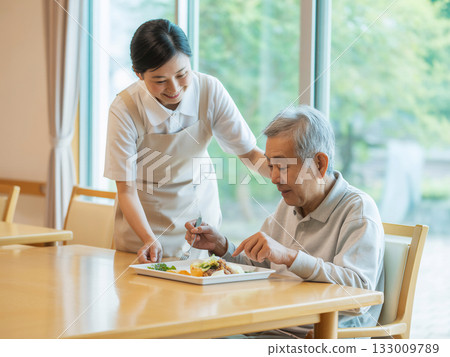 一位微笑的女性護理員正在協助用餐（生成式人工智慧） 133009789