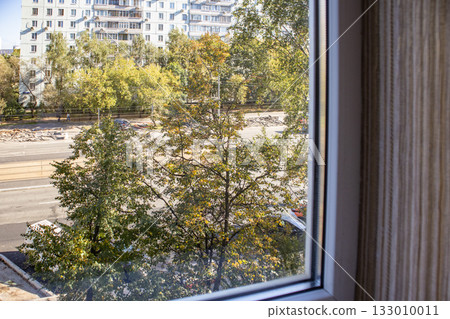 Textured beige wall by window city view and trees soft daylight horizontal frame 133010011