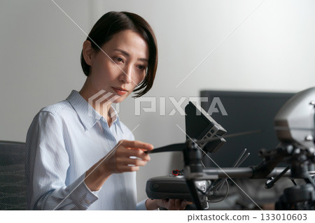 A woman checking the operation of a drone 133010603