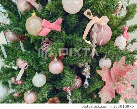Pink and gold Christmas ornaments on green tree close up 133010970