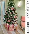 Christmas tree with pink ornaments and gifts in cozy interior 133011015